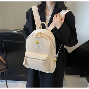 Close-up of beige crocodile pattern texture and gold metal logo on the fashion backpack