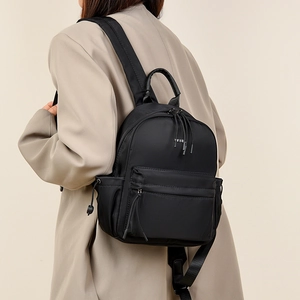 Minimalist black travel backpack with YSD logo shown on model in neutral setting