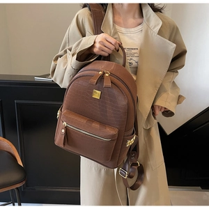 Detail of brown crocodile pattern backpack with gold hardware and stylish front logo plate