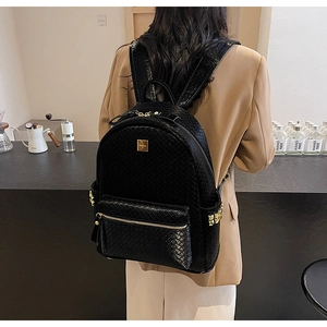 Detail of black woven leather backpack showing gold hardware and front zipper pocket