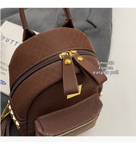 Detail of brown woven faux leather mini backpack featuring smooth dual metal zippers