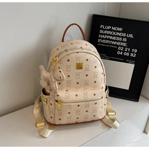 Detail of beige backpack with bear prints, golden rivets, and bow charm accessory