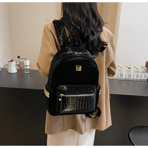 Close-up of black crocodile pattern backpack with gold hardware and star studs details