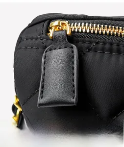 Détail du sac à bandoulière en nylon matelassé noir avec zip doré et tirette en cuir
