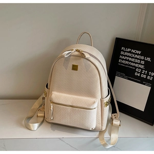 Close-up of woven texture and golden rivets on a stylish beige faux leather backpack
