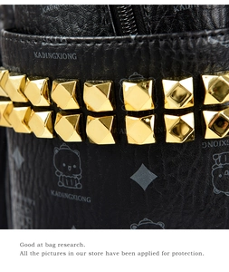 Close-up of black lychee grain leather bag with golden pyramid studs and bear pattern