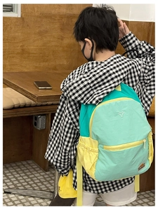 Rear view of child wearing a multi-color water-resistant nylon backpack in a room