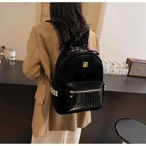 Detail of black crocodile texture backpack with gold studs in a cafe setting