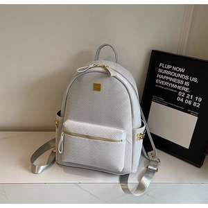 Detailed close-up of light grey woven texture backpack with golden pyramid studs