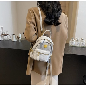 Detailed view of grey woven mini backpack with gold hardware worn by a model