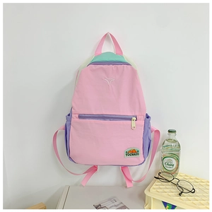Detail of color-block kids backpack showing pink nylon fabric with mint green accents