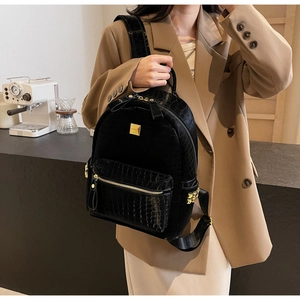 Detail of black mini backpack featuring croc-pattern leather and gold metal hardware