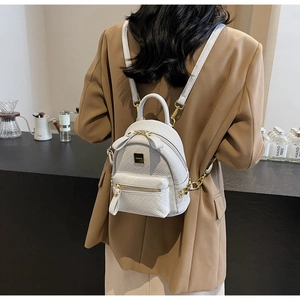 Rear view of a model wearing a light gray woven texture mini backpack with golden hardware