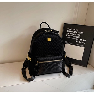 Detail of black leather backpack with woven texture and gold pyramid stud accents