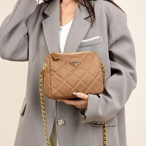Détail d'un sac à bandoulière matelassé marron avec chaîne dorée et logo triangle