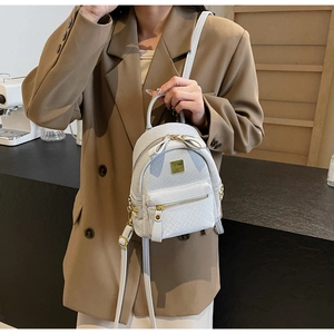 Close-up of white woven texture mini backpack with gold hardware worn by model