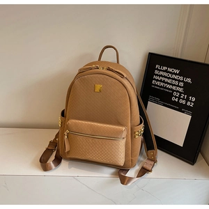 Close-up of brown woven texture backpack with golden metal plate and rivet details