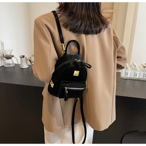 Detailed view of mini black backpack featuring gold hardware and glossy woven texture