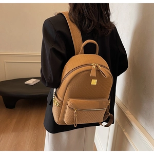 Detail of tan woven texture backpack with golden spike studs and metallic zipper