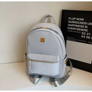 Detail shot of grey crocodile embossed backpack with premium gold metal hardware and rivets