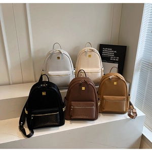 Close-up of textured backpacks in five colors with woven details and gold hardware