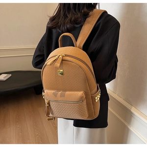Detail of khaki backpack with woven texture and gold metallic studs and logo plate