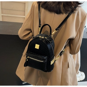 Detail of woven texture black mini backpack with gold zippers and side rivet accents