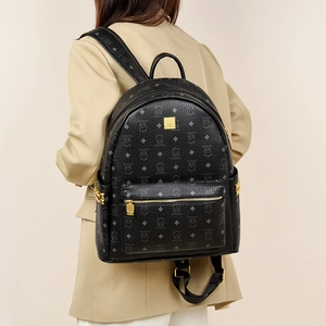 Detail of black leather backpack with cat pattern, gold studs, and metallic hardware
