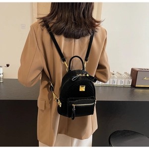 Close-up of a quilted black leather mini backpack with golden metal hardware and branding