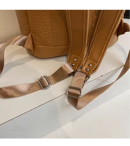 Detail of adjustable nylon shoulder strap with silver metal buckle on brown backpack
