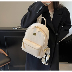 Detail of cream woven leather backpack featuring gold rivets and metallic logo plate