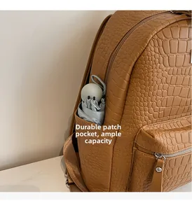 Close-up of side pocket on brown crocodile pattern backpack holding a folded umbrella
