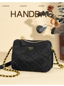 Détail du sac à bandoulière noir matelassé avec chaîne dorée et logo triangle en métal