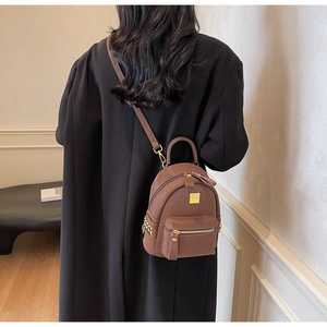 Detail showing brown mini backpack with woven texture and gold metal hardware zippers