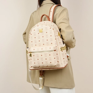 Detail of beige teddy bear monogram backpack with golden studs on side and metal zipper