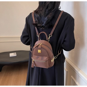 Close-up of woven texture brown mini backpack with gold hardware and side rivets