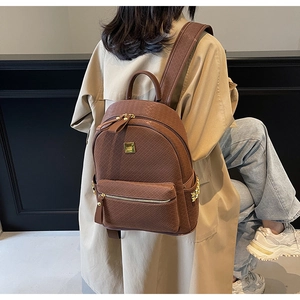 Detail of brown quilted backpack featuring a golden star charm and zipper texture