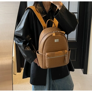 Detail of brown crocodile pattern backpack with silver zippers on a fashion model