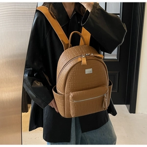 Detail of soft brown crocodile embossed leather backpack with adjustable woven straps