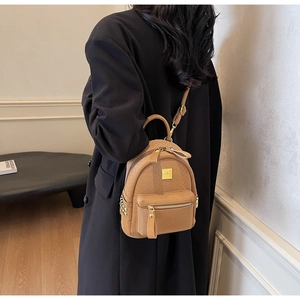 Detail view of khaki mini backpack with quilted leather texture and gold zipper accents