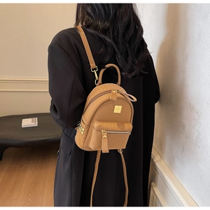 Close-up of woven camel leather mini backpack showing golden zipper and rivet details
