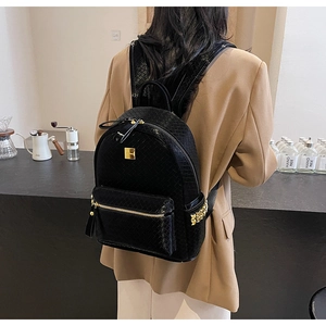 Close-up of black woven texture backpack featuring gold zipper and metal logo plate