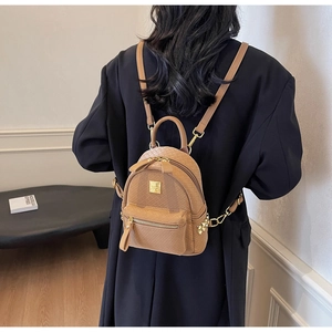Rear view of a model wearing the brown woven mini backpack with gold hardware details