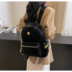 Detail of black woven texture backpack featuring gold rivets and sleek metal zippers