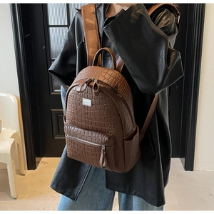 Detailed view of dark brown crocodile texture on a stylish leather backpack