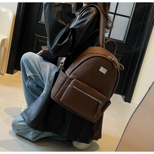 Detail of dark brown faux leather backpack with crocodile pattern and silver metal hardware