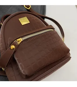 Close-up of dark brown crocodile pattern leather backpack with gold metal zipper and logo