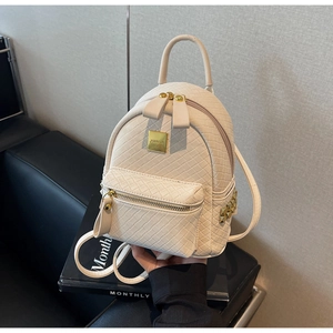 Detailed view of beige woven leather backpack with gold rivets and metallic hardware