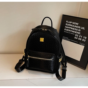 Close-up of black woven leather backpack featuring gold studs and metal zipper details