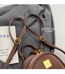 Detail of adjustable straps and gold metal zipper on brown crocodile textured backpack